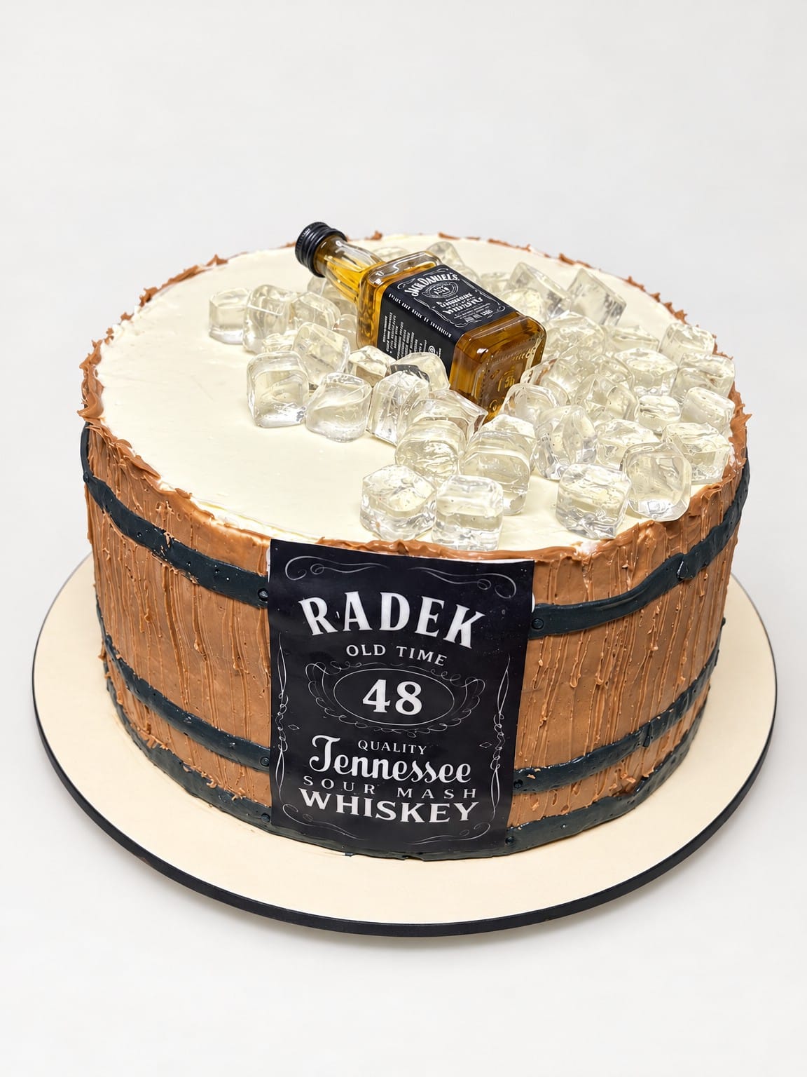 Tort w stylu beczki z ciemnymi obręczami, etykietą RADEK 48 oraz butelką whiskey i przezroczystymi dekoracjami na jasnym wierzchu.