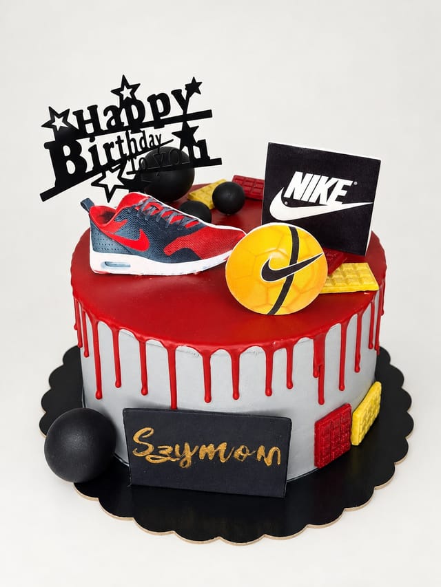 Tort z jasnoszarymi bokami, czerwonymi zaciekami, dekoracją buta Nike, żółtej piłki i tabliczką z imieniem Szymon.